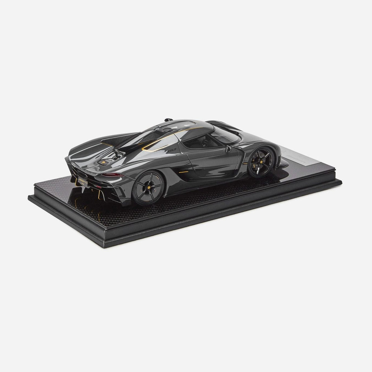 A dark gray metallic model of a Jesko Absolut displayed on a black rectangular base against a light gray background.