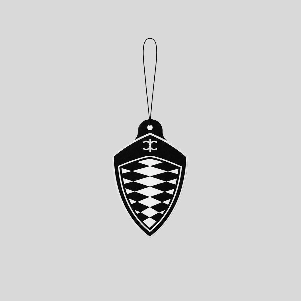 A black Koenigsegg Shield hanging car air freshener with a loop at the top, shown on a plain light gray background.