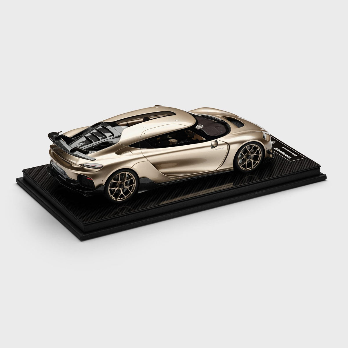 A metallic champagne-gold model Gemera Skumpa displayed on a black rectangular base against a light gray background.