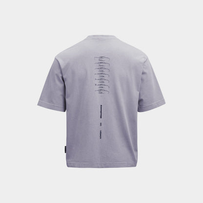 A purple short-sleeve t-shirt shown from the back, featuring a vertical graphic print of stacked cars in black on the upper back and a small black tag near the bottom left hem, set against a solid light gray background.